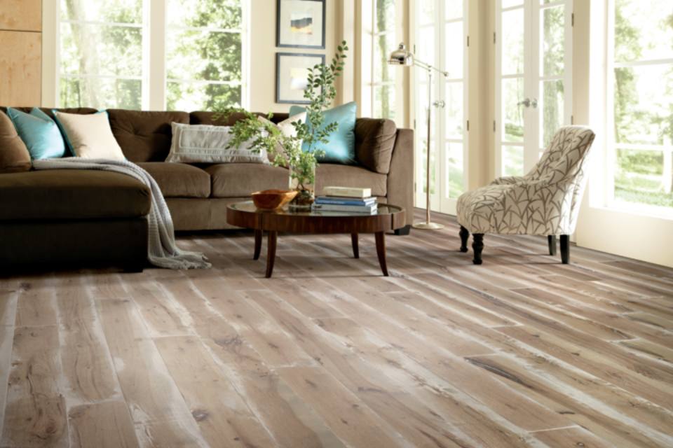 rustic hardwood flooring in living room with brown couch and patterned chair.